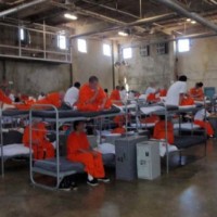 Prisoners seated on closely-spaced bunk beds in dorm