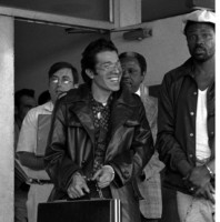 Man in leather jacket with briefcase, chained at the wrist to another man