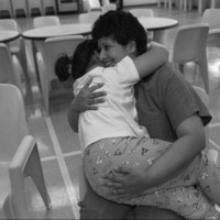 A female detainee embraces a young girl seated in her lap