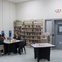 Three women prisoners seated and talking the library