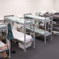 A row of dorm bunk beds, mostly empty, some with bedding