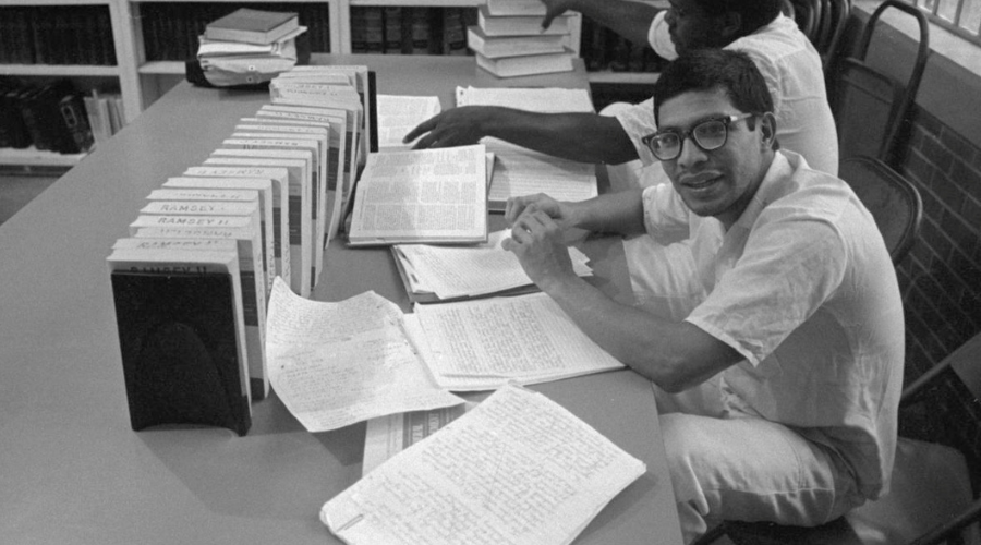 Two prisoners sit in law library in front of books and handwritten briefs